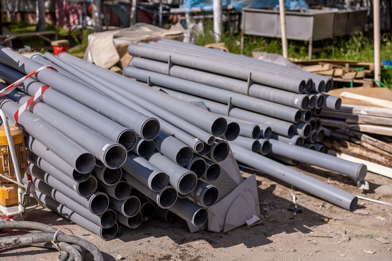 lengths of new gravity sewer pipe stacked at a job site, the alternative that any sewer pipe relining quote is measured against