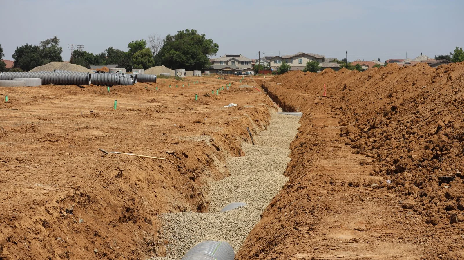 an open trench and bedding stone along a suburban street where an underground water leak was traced before digging