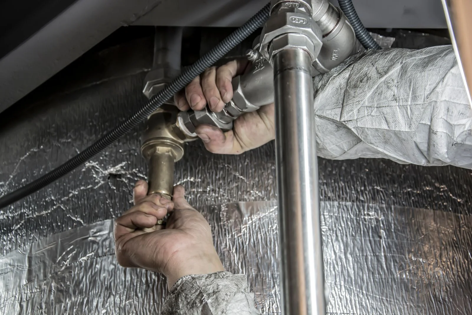 a plumber's hands checking a pressurised supply fitting during water leak detection cleveland tn homeowners book