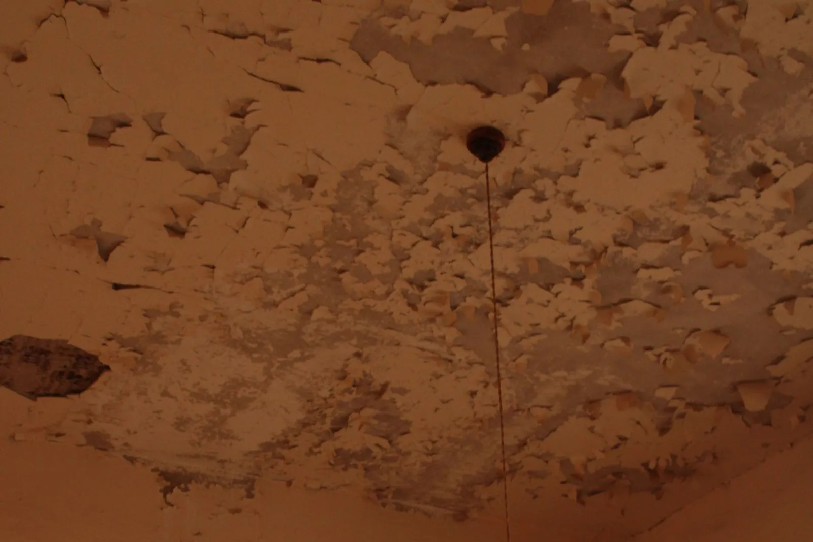 a ceiling blistered and stained by water that has come through from somewhere above it